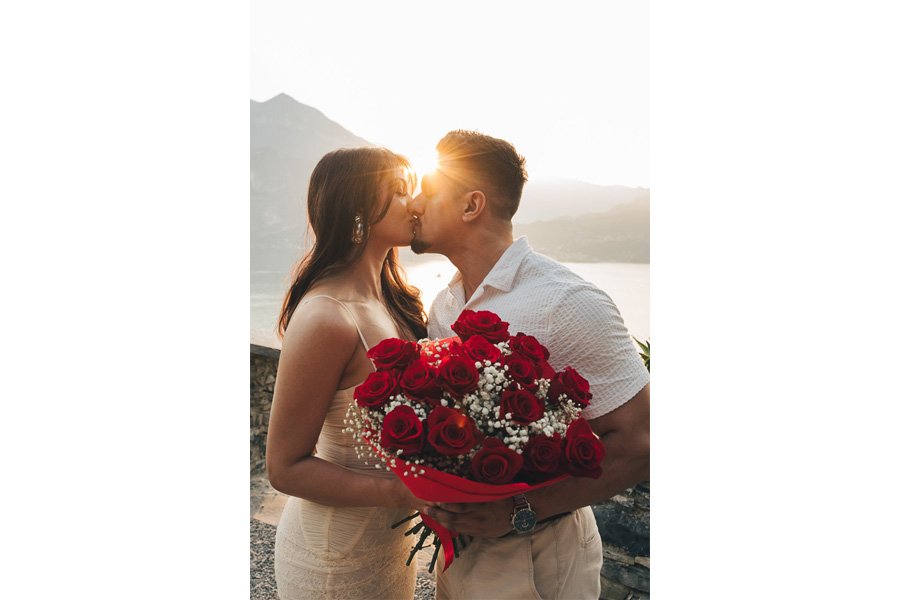 I Neo Fidanzati Si Baciano Fra I Raggi Del Sole Del Tramonto Mentre Tengono Un Mazzo Di Rose Rosse I Neo Fidanzati Si Baciano Fra I Raggi Del Sole Del Tramonto Mentre Tengono Un Mazzo Di Rose Rosse