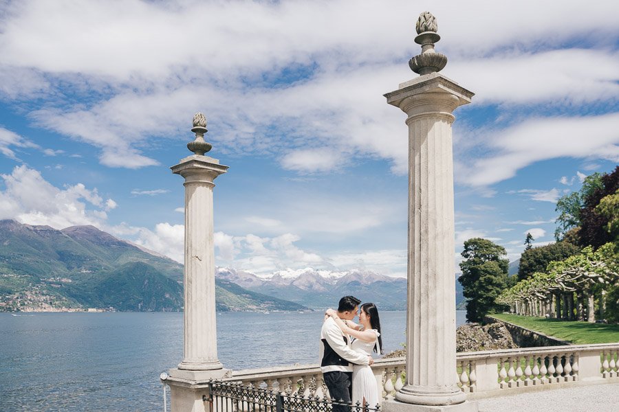 Una Coppia Di Fidanzati Si Abbraccia Teneramente A Villa Melzi Davanti Alle Montagne Innevate Del Lago Di Como Una Coppia Di Fidanzati Si Abbraccia Teneramente A Villa Melzi Davanti Alle Montagne Innevate