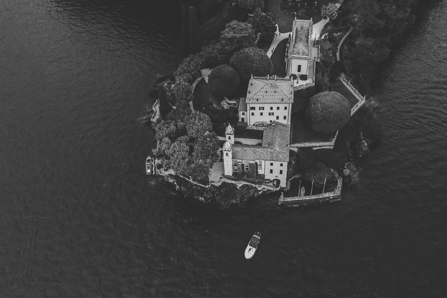 Villa Del Balbianello Photographed By Drone With A Boat Nearby Carrying A Newly Engaged Couple 