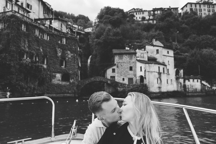 Young Engaged Guys They Kiss Each Other On Wooden Boat In Lake Como Near Orrido di Nesso